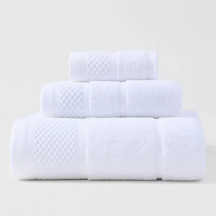 3-piece thick cotton towel set in white, folded and rolled with waffle texture bands.
