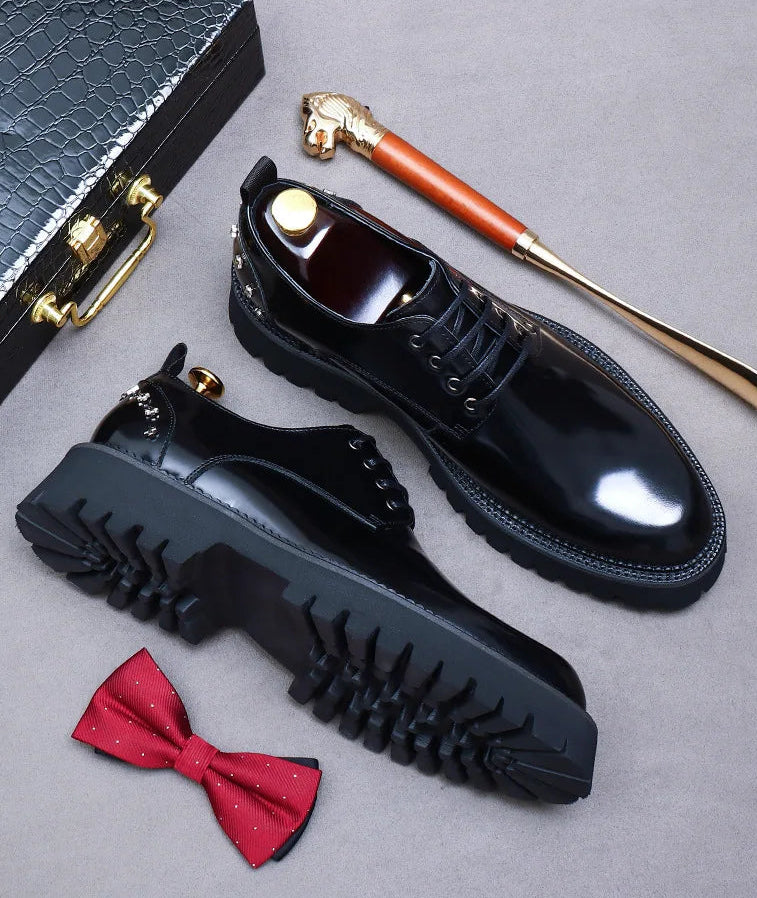 Black men's shoes with a shoe brush, red bow tie, and shoe horn on a gray surface.
