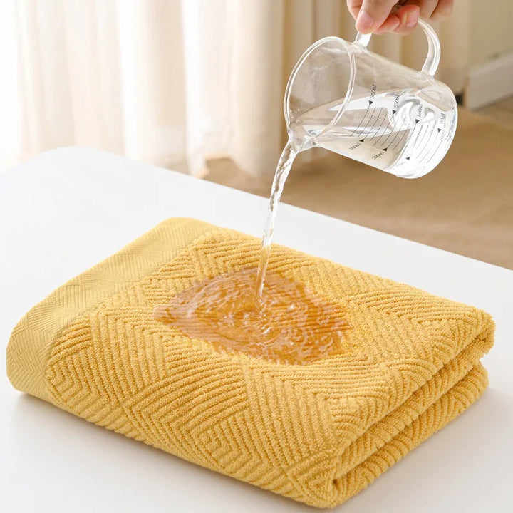Mustard yellow cotton bath towel folded on a table with water being poured