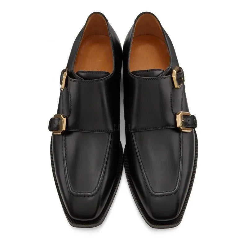 Pair of black leather shoes with gold buckles on a white background, branded 'Stiglitz'.