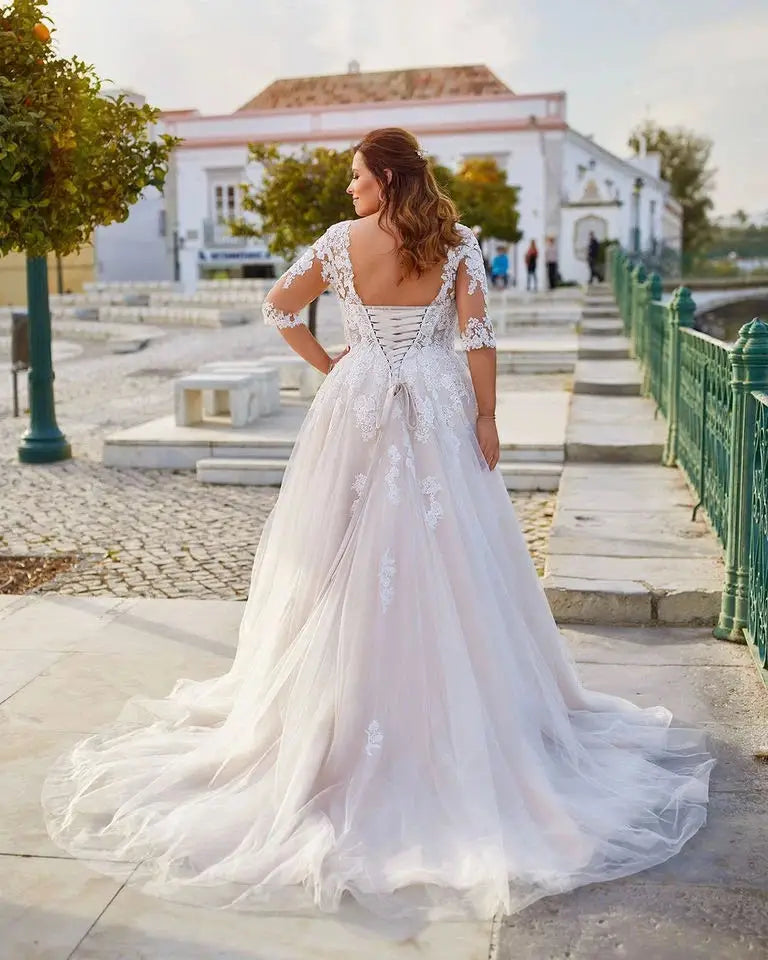 Ivory lace bridal gown in back view with cap sleeves, open back, and flowing tulle skirt