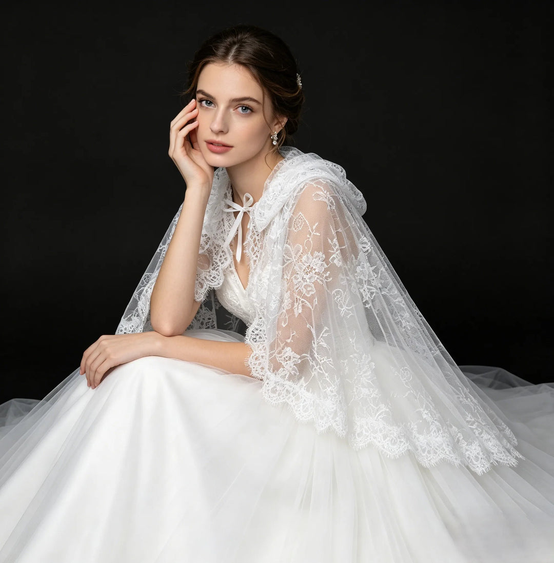 Off-white hooded lace cape with floral embroidery, sheer overlay, and scalloped neckline