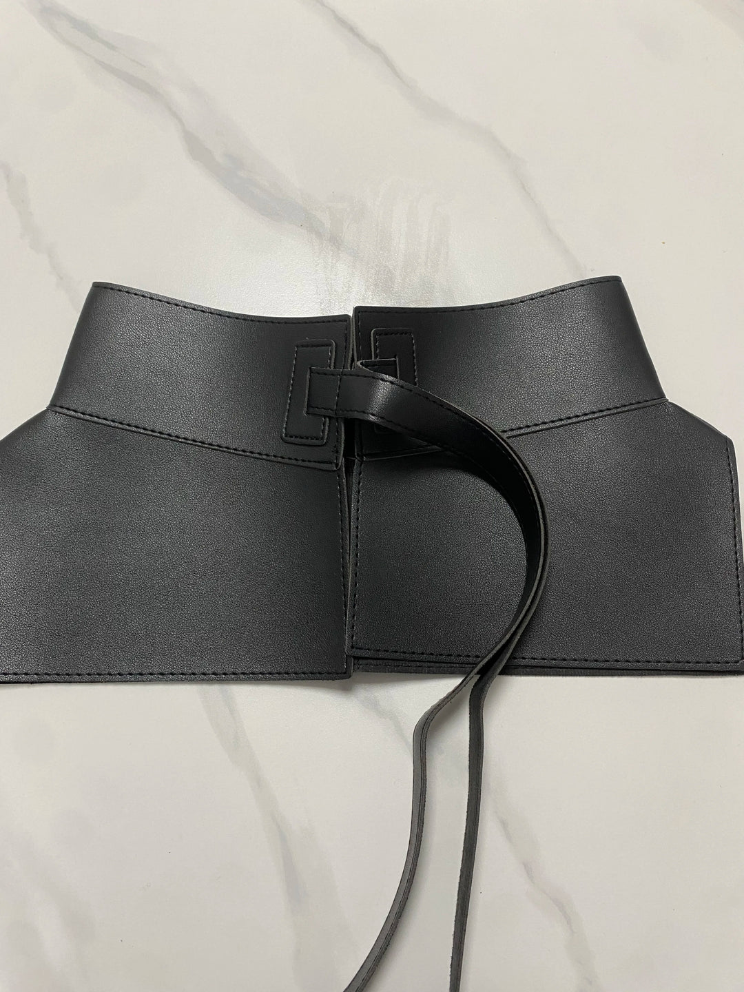 Wide black waist belt with square buckle, center ring detail, and long tie cords