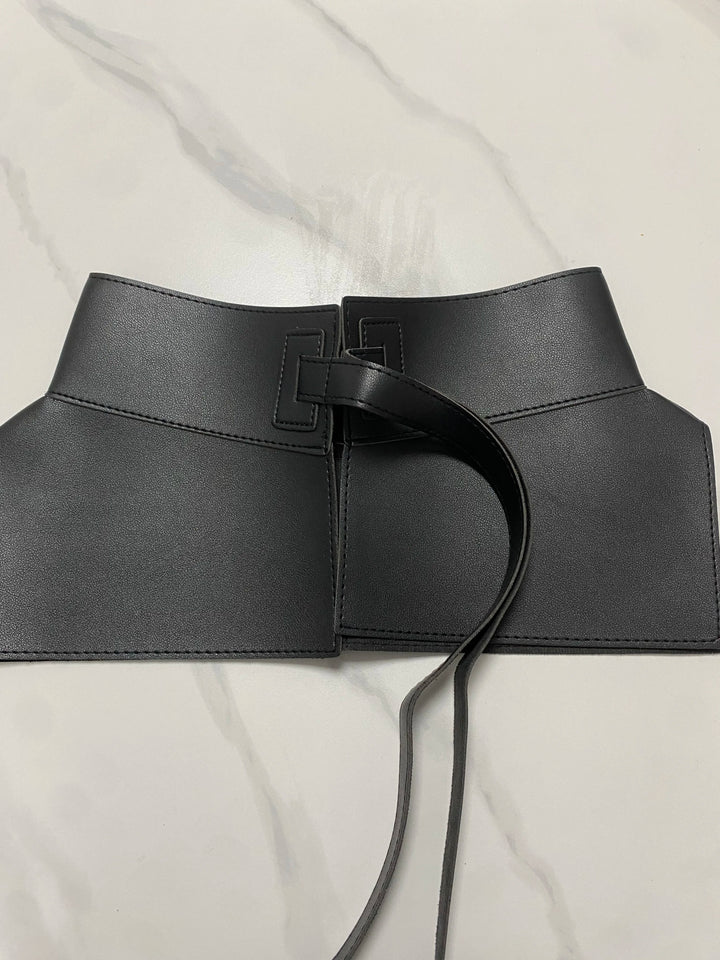 Wide black waist belt with square buckle, center ring detail, and long tie cords