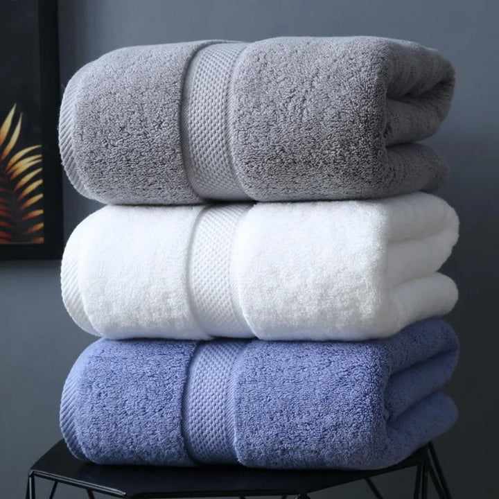 Luxury organic cotton bath towel set in grey, white, and blue, neatly rolled and stacked