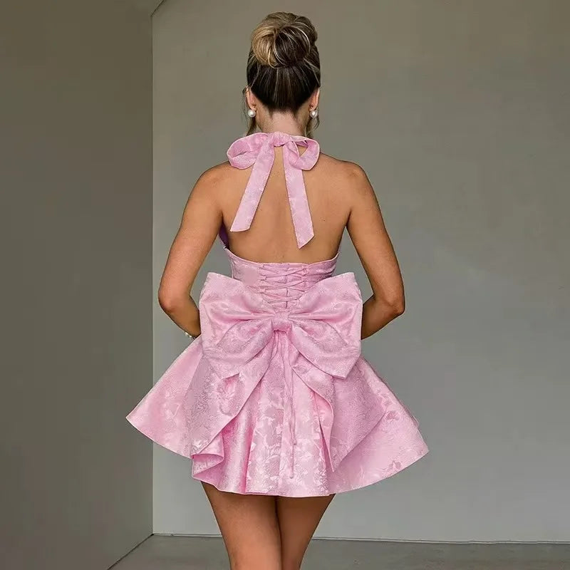 Pink mini A-line halter dress from back with tie bow and open-back cut