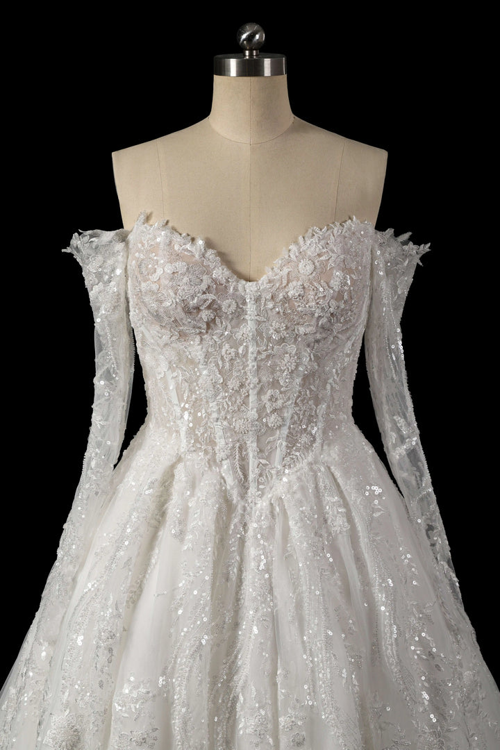 White sequin bridal gown with corset bodice, off-shoulder neckline, and long sleeves