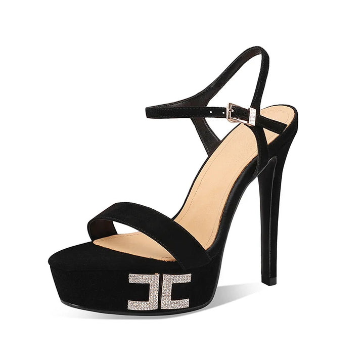 Black suede platform heeled sandals with open toe and metal logo ornament