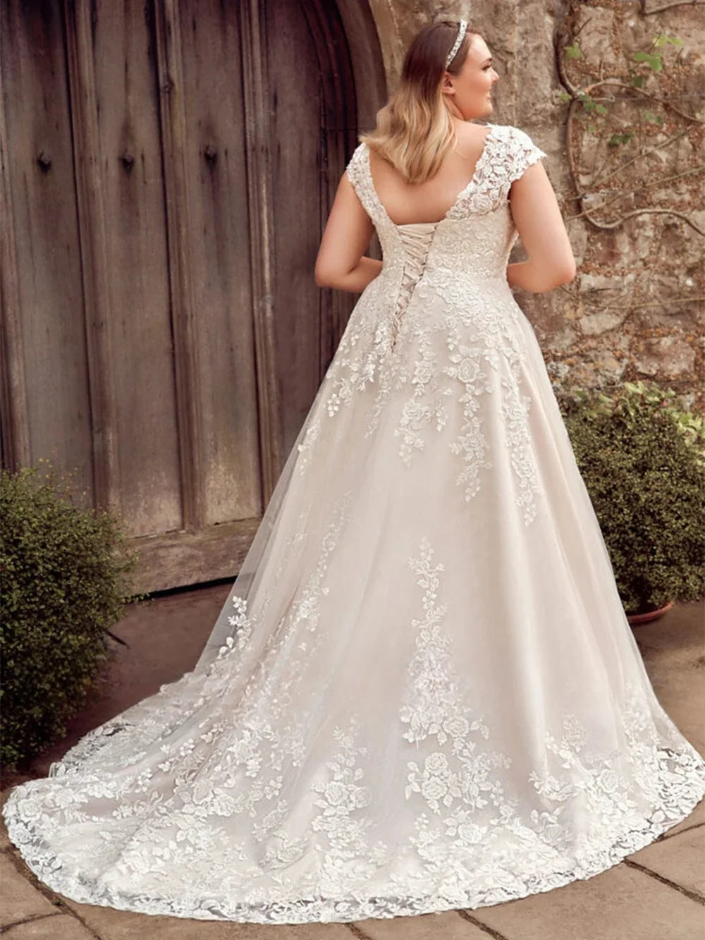 Woman wearing a white lace wedding dress in an outdoor setting.