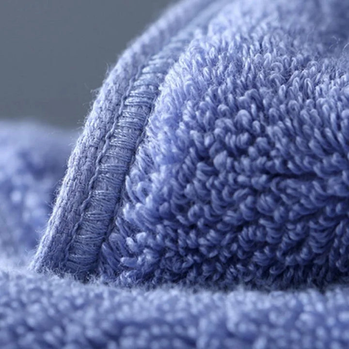 Bath towel in blue, close-up of stitched hem and looped terry texture