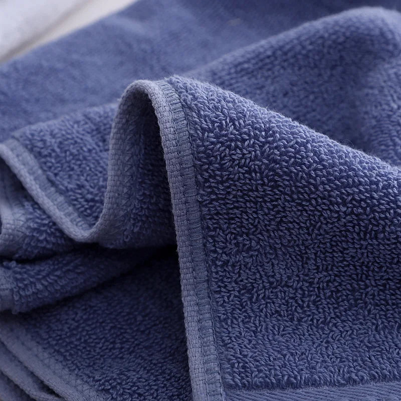 Blue bath towel with textured terry loops and a stitched border edge, close-up