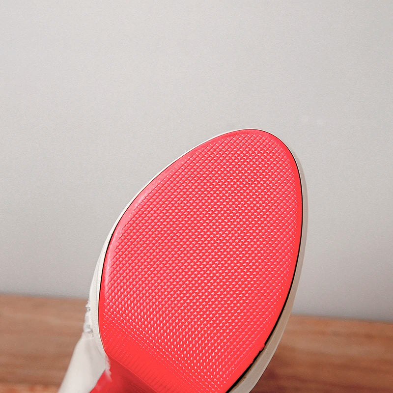 Red textured outsole underside of a cream ankle boot