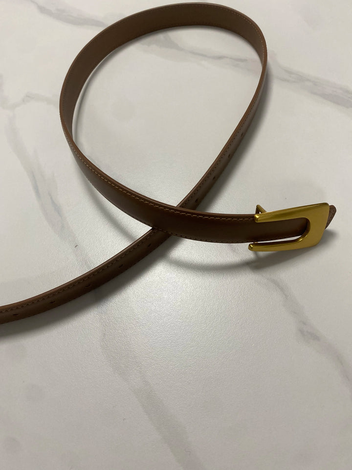 Narrow brown leather waist belt with curved end, gold-tone buckle, and adjustment holes
