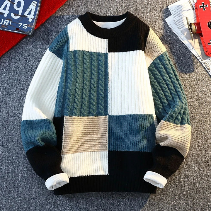 Patchwork knit sweater with black, blue, teal, and cream blocks; ribbed cuffs and hem.