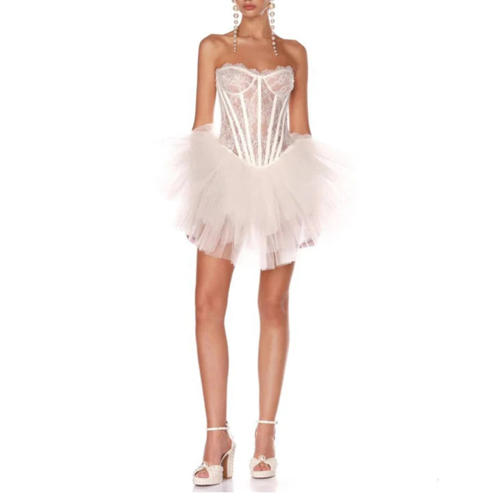 A woman modeling a white strapless dress with a tiered ruffled skirt and a sweetheart neckline.