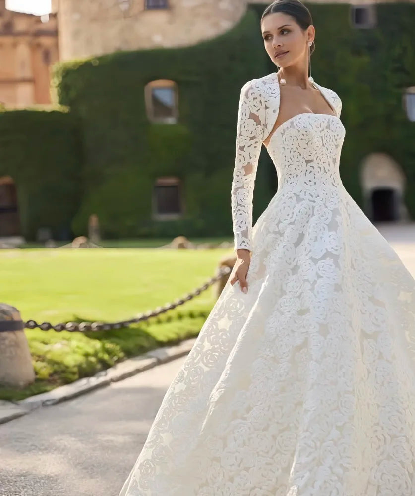 White lace bridal gown with square neckline, long sleeves, and fitted full skirt