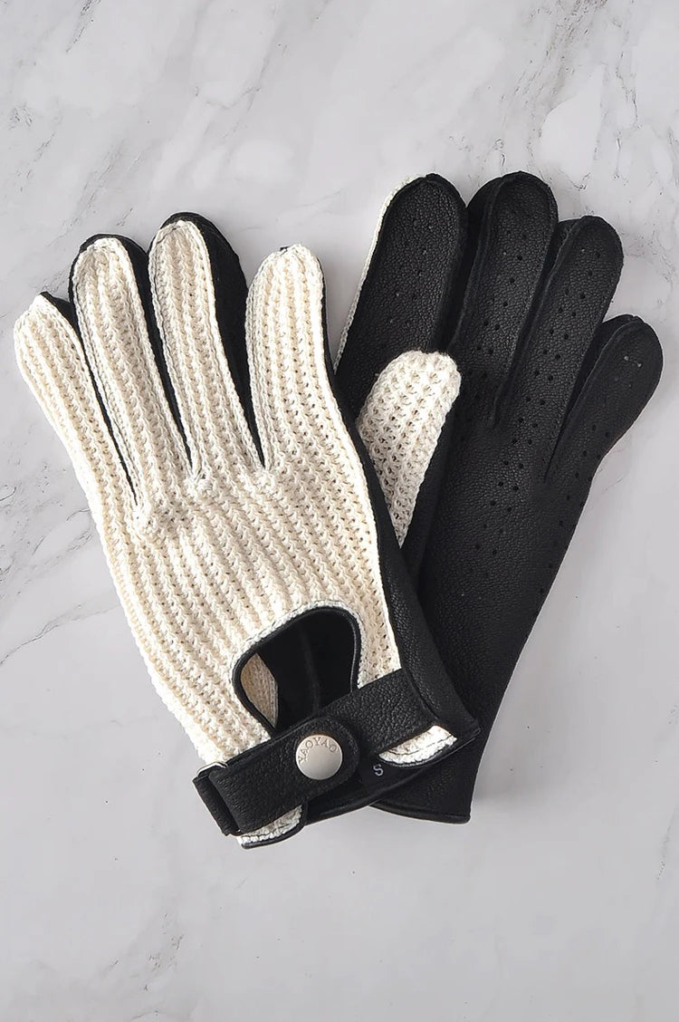 Pair of white knitted gloves with black leather backs and perforation detail.