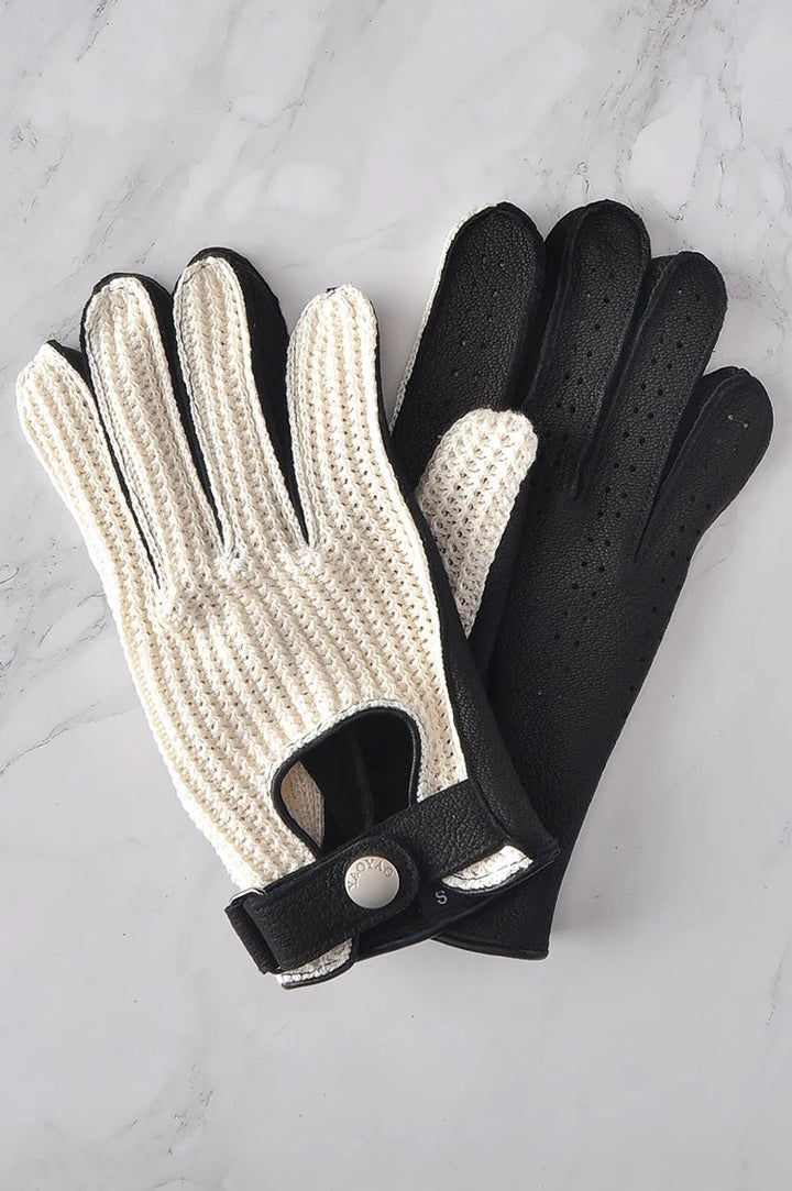 Pair of white knitted gloves with black leather backs and perforation detail.