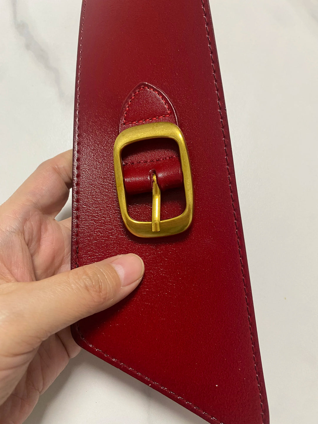 Red leather corset belt with oval gold buckle, stitched edge, strap end detail