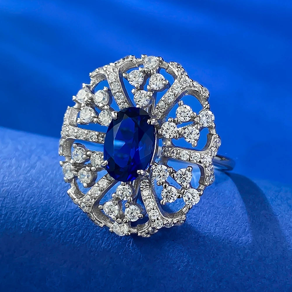 Silver oval-cut blue gemstone ring with halo of clear stones, prong-set center