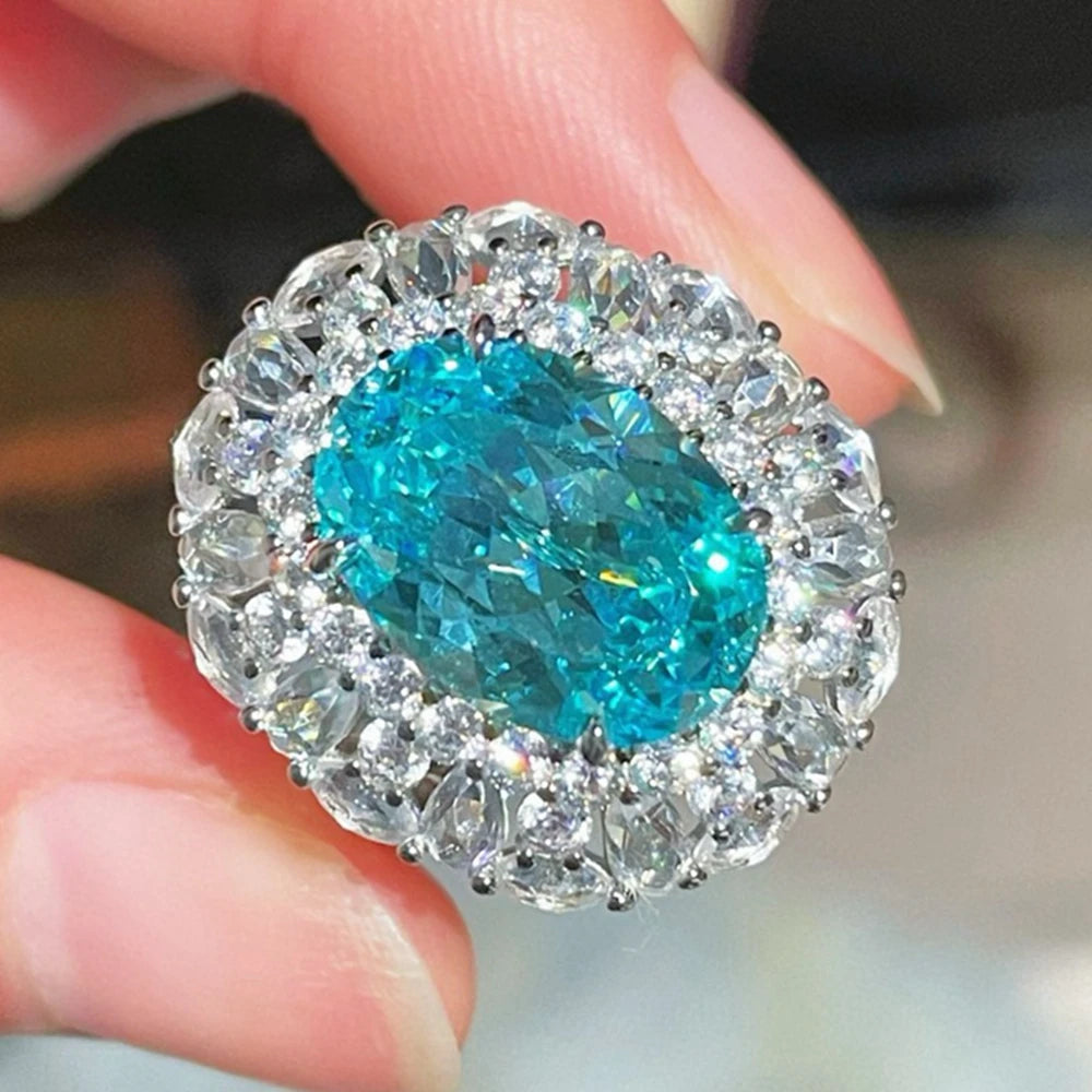 Sterling silver oval blue-teal gemstone ring with clear halo of stones, front view