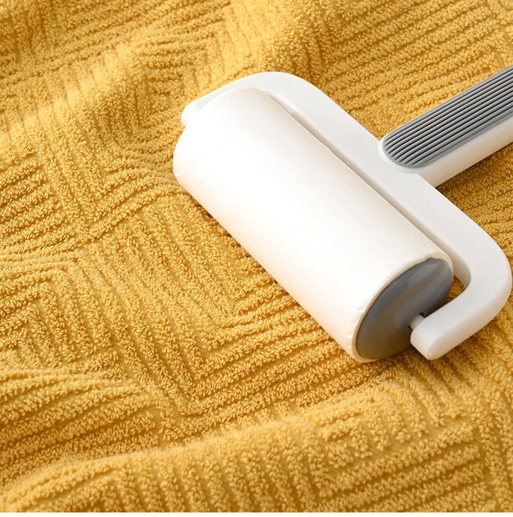 Mustard yellow cotton towel surface with a handheld lint roller on top