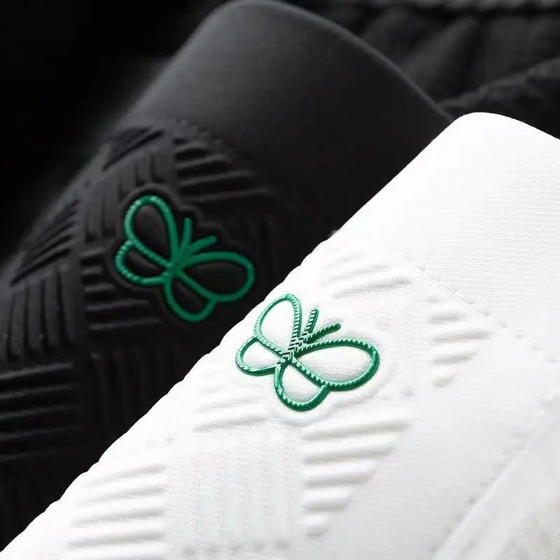 White cotton track pants close-up of green butterfly logo and stitched waffle texture