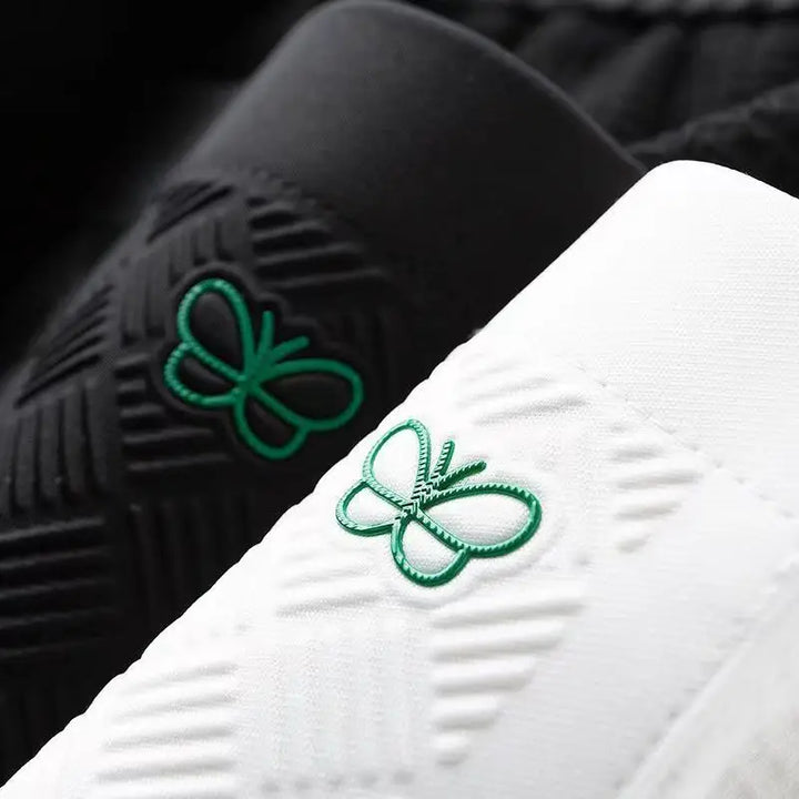 White cotton track pants close-up of green butterfly logo and stitched waffle texture