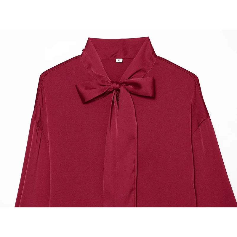 Red satin blouse front with large bow at collar and long sleeves.