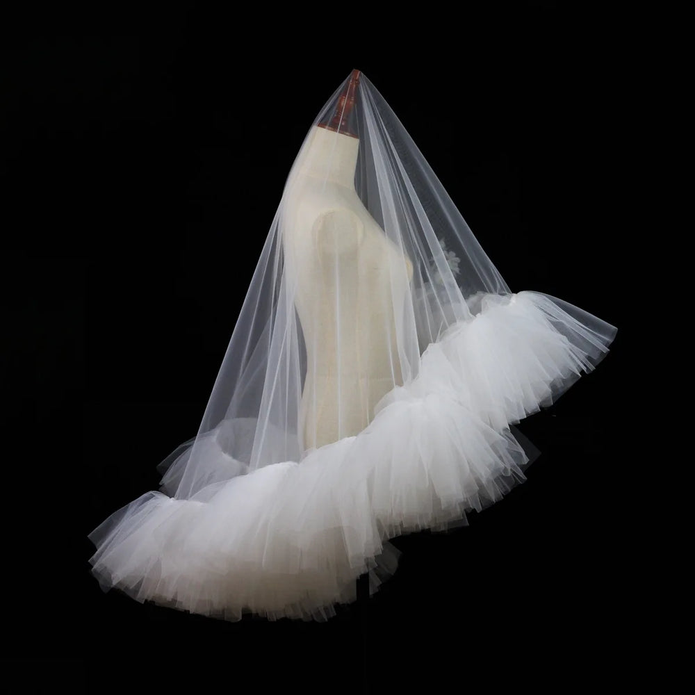 White tulle bridal veil with layered ruffle trim, angled view