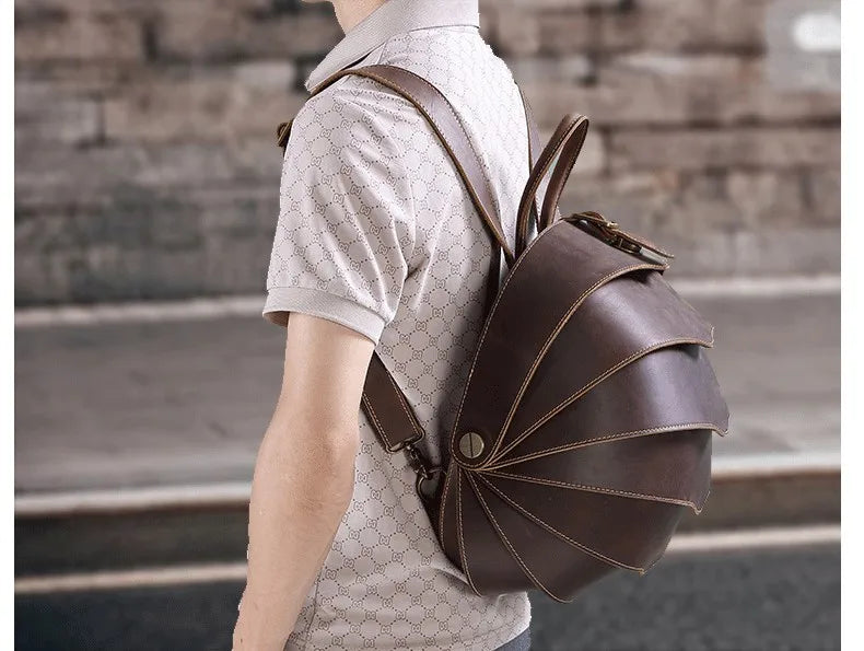 Brown leather round backpack side view with adjustable strap and curved stitched flap.
