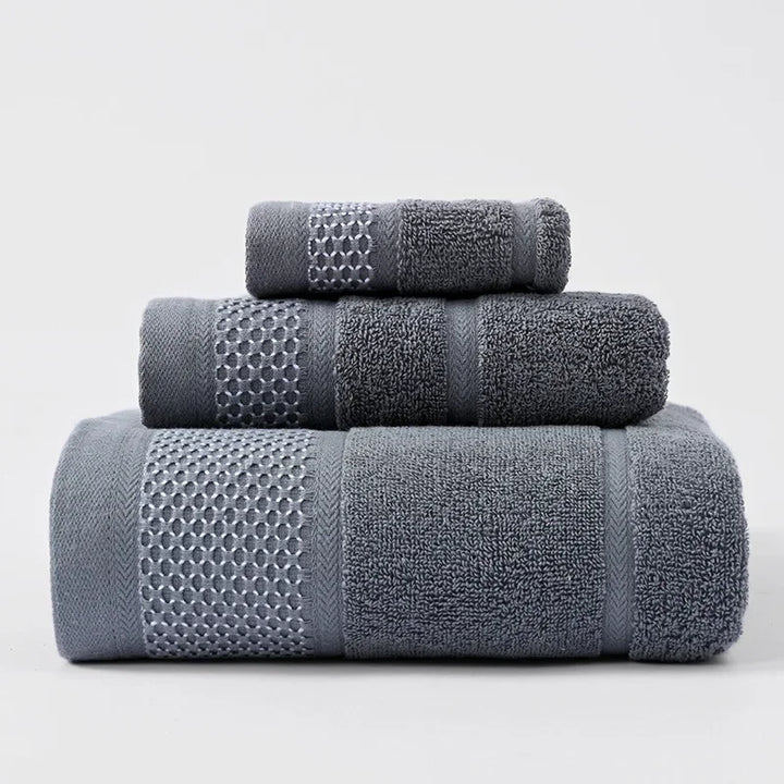 Thick cotton towel set in dark gray, folded in stacked rolls with textured bands.