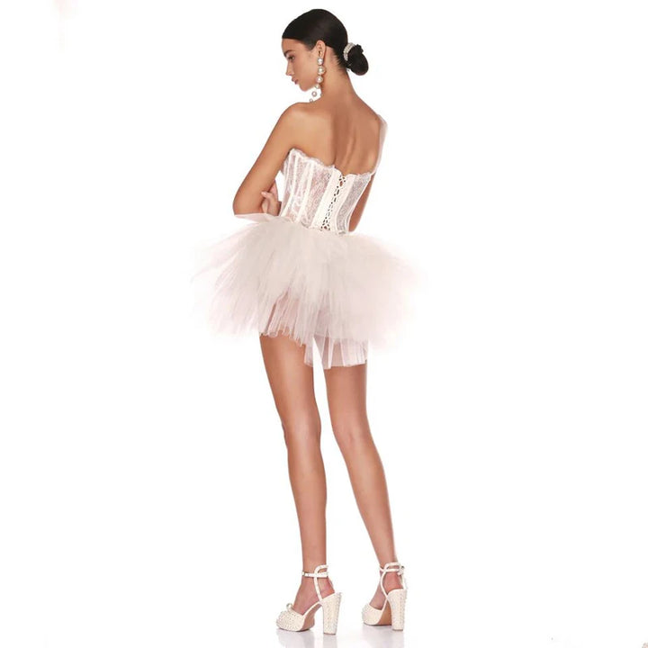 Model wearing a white tutu dress from the back on a white background.