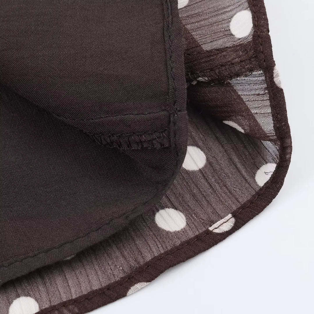 Women’s chiffon blouse hem detail, dark brown with white polka dots and stitched finish