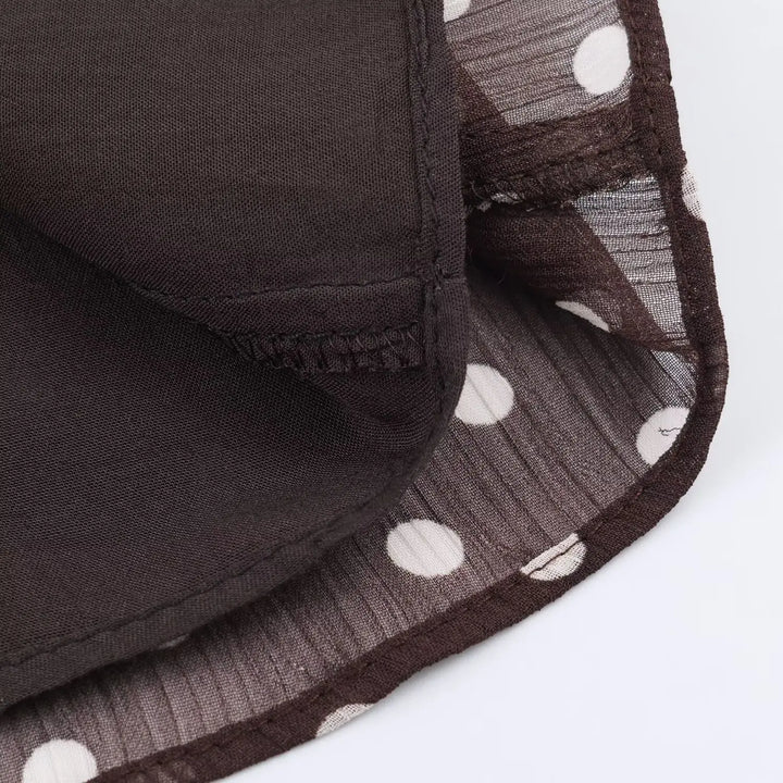 Women’s chiffon blouse hem detail, dark brown with white polka dots and stitched finish