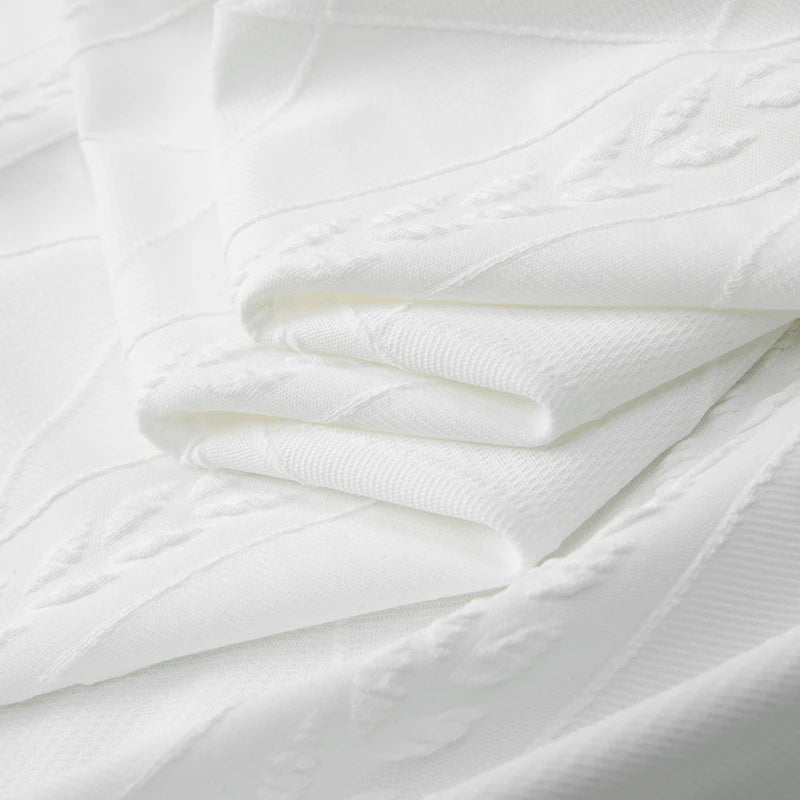 Folded white knit shirt fabric with raised textured pattern and soft ribbed surface