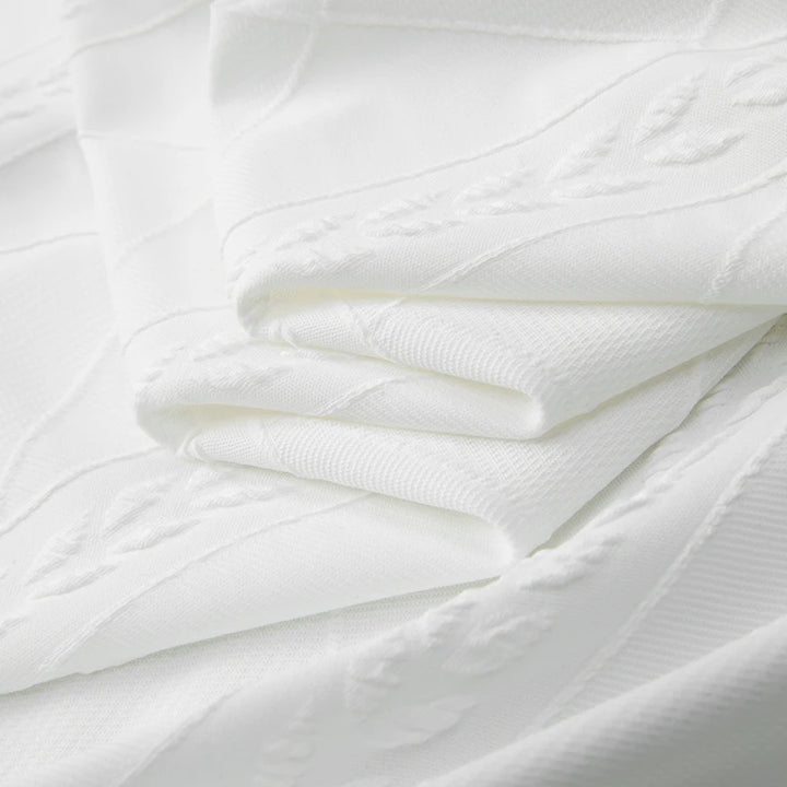 Folded white knit shirt fabric with raised textured pattern and soft ribbed surface