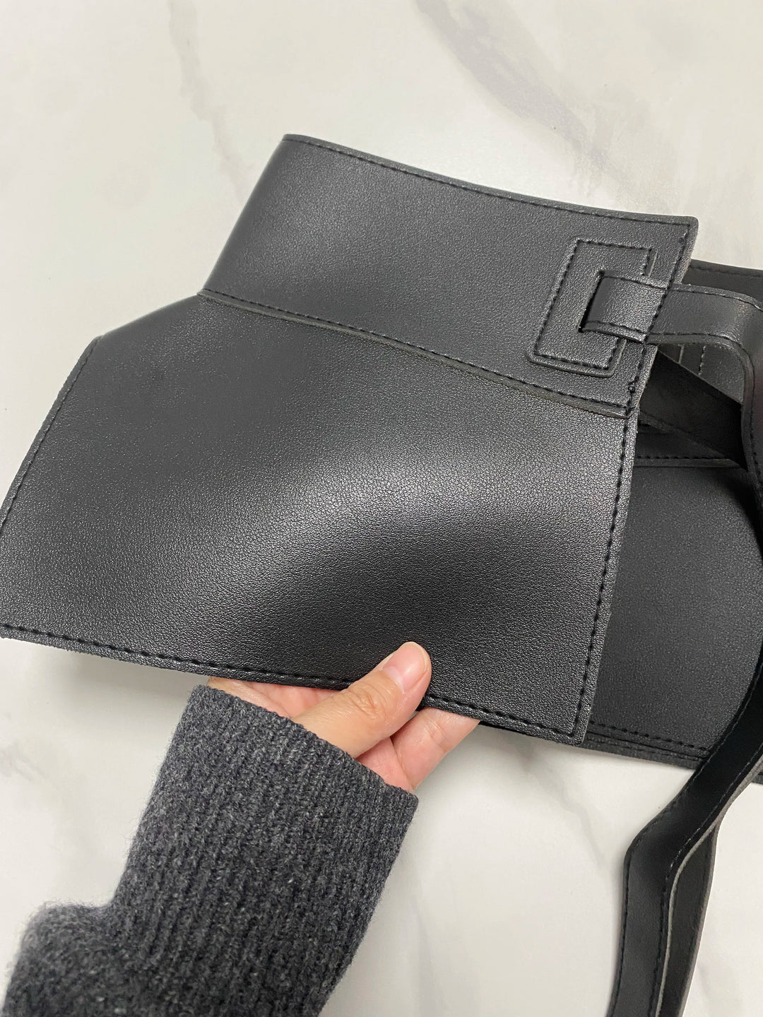 Wide black waist belt with adjustable buckle; shown with hand holding the front
