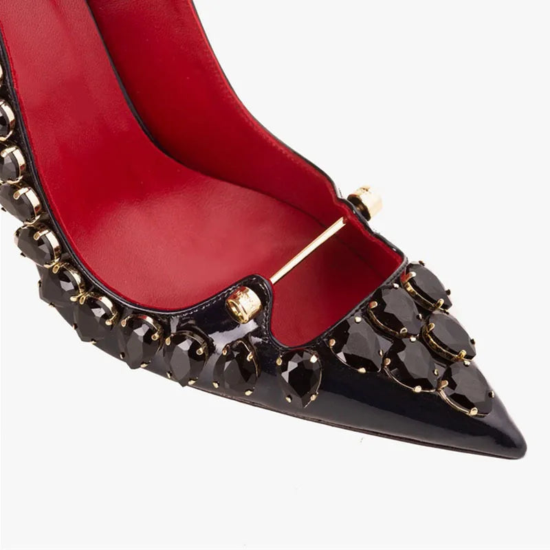 Close-up of black crystal heel pump with red lining and buckle strap detail