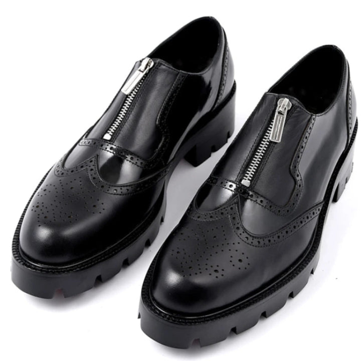 A pair of black leather men's brogue shoes with a front zip design and a rubber outsole.