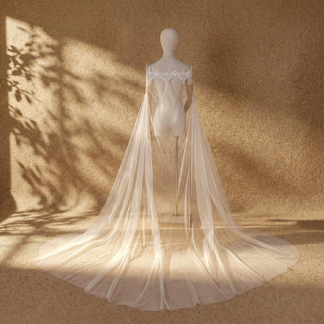 Mannequin wearing off-white bridal dress with lace trim and long sheer tulle veil