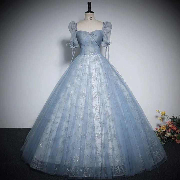 Light blue shiny ball gown with puff sleeves, bow ties, and full tulle skirt on mannequin