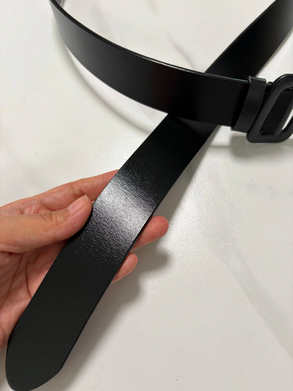 Narrow black leather belt strap with adjustable hole section