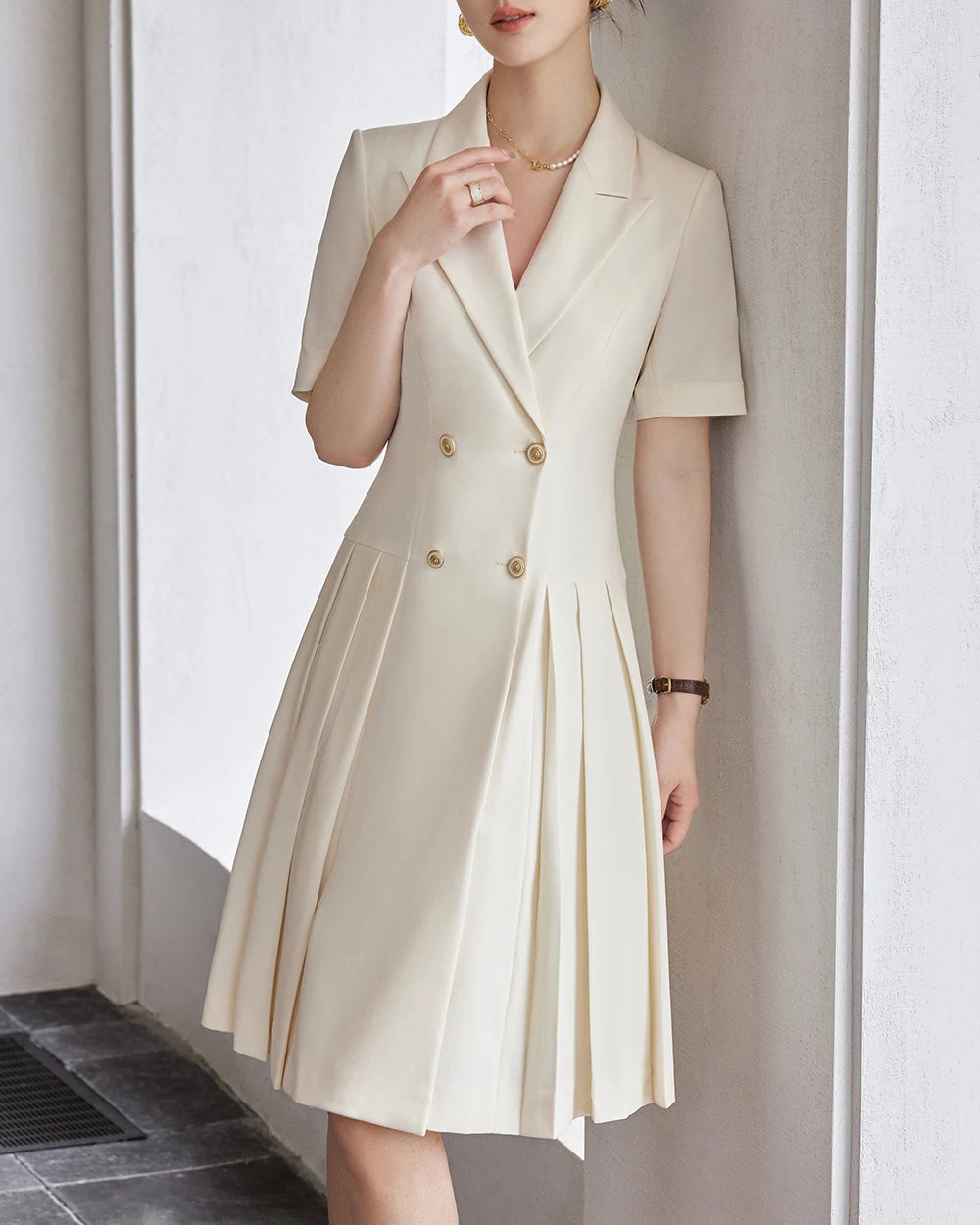 Beige A-line dress with notched lapels, short sleeves, pleated skirt, gold buttons