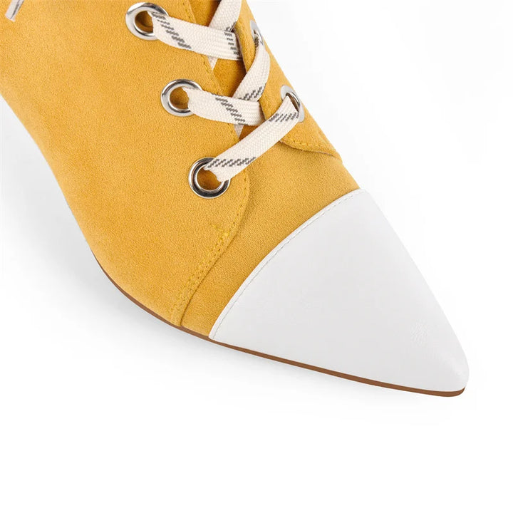 Yellow faux suede boot close-up: lace-up eyelets and pointed white-trim toe