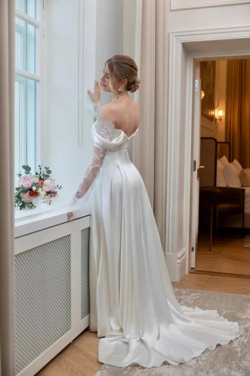 Back view of ivory satin bridal gown with lace sleeves and fitted, flowing A-line skirt