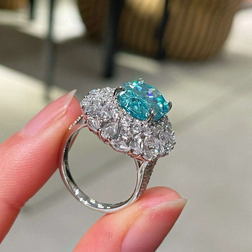 Sterling silver blue-teal oval gemstone ring with round crystal halo, side view