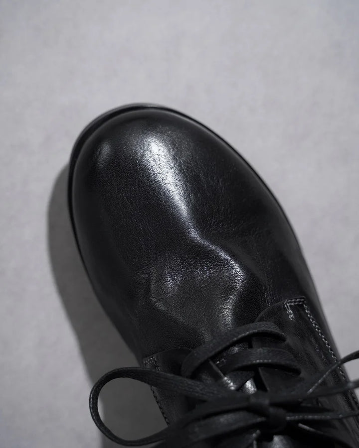 Black leather lace-up flat shoe toe and laces close-up