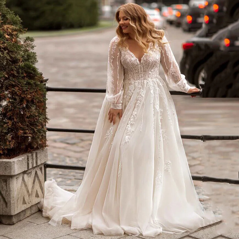 Ivory bridal ballgown with lace bodice, long sheer sleeves, and full tulle skirt