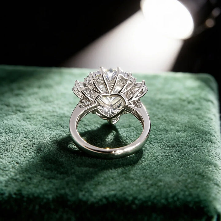 Sterling silver halo ring with round center stone, side view on soft green surface.